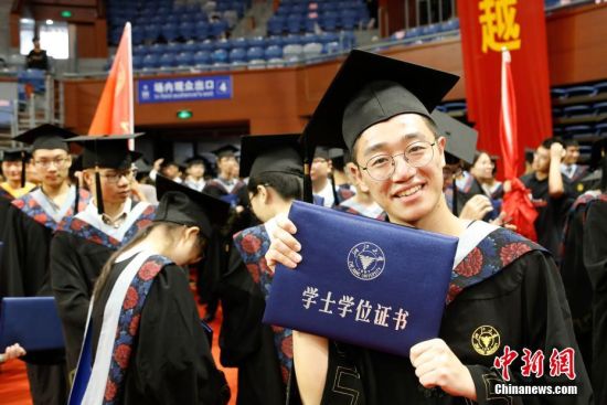 一位毕业生在展示刚刚拿到的学位证书。 中新社记者 王远 摄